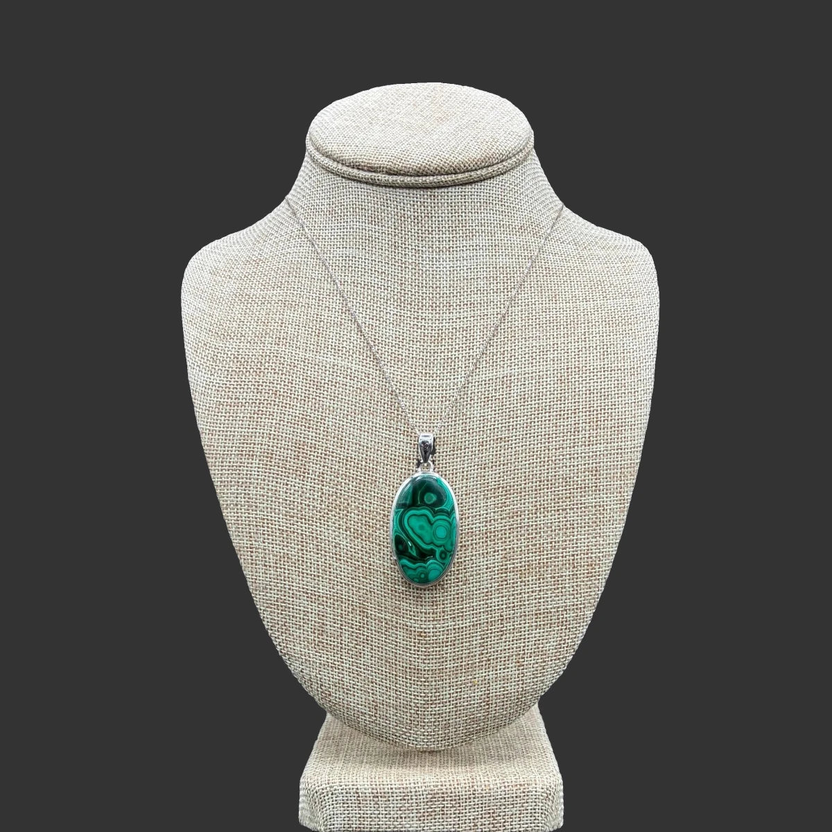 Front view of this sterling silver malachite necklace, in front of a black background.