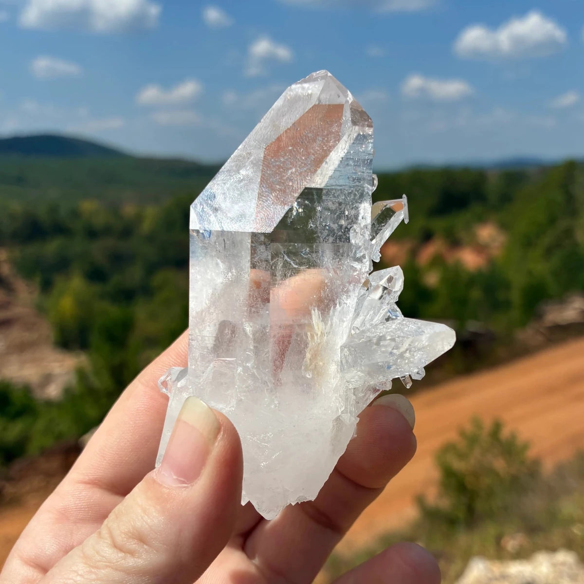 Right side of this quartz crystal point, in front of a blue sky.