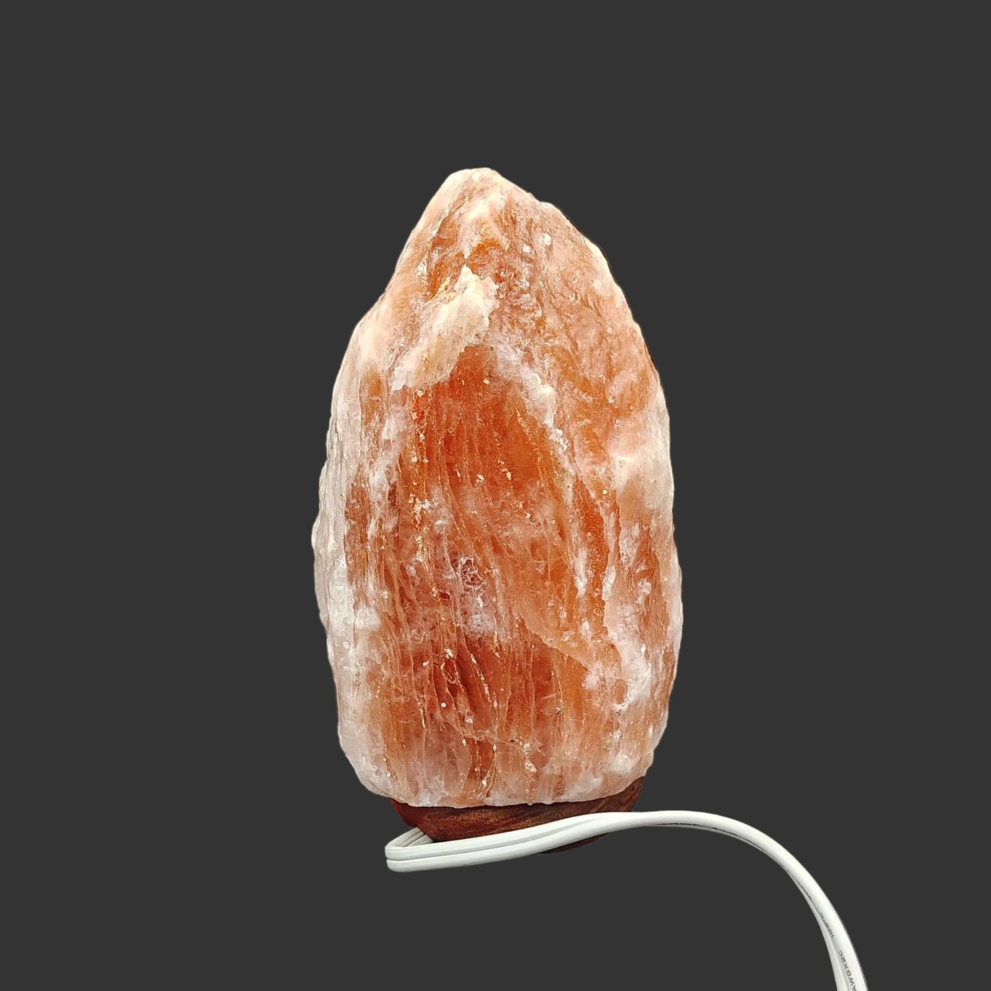 The back side of this pink Himalayan salt lamp in front of a black background.