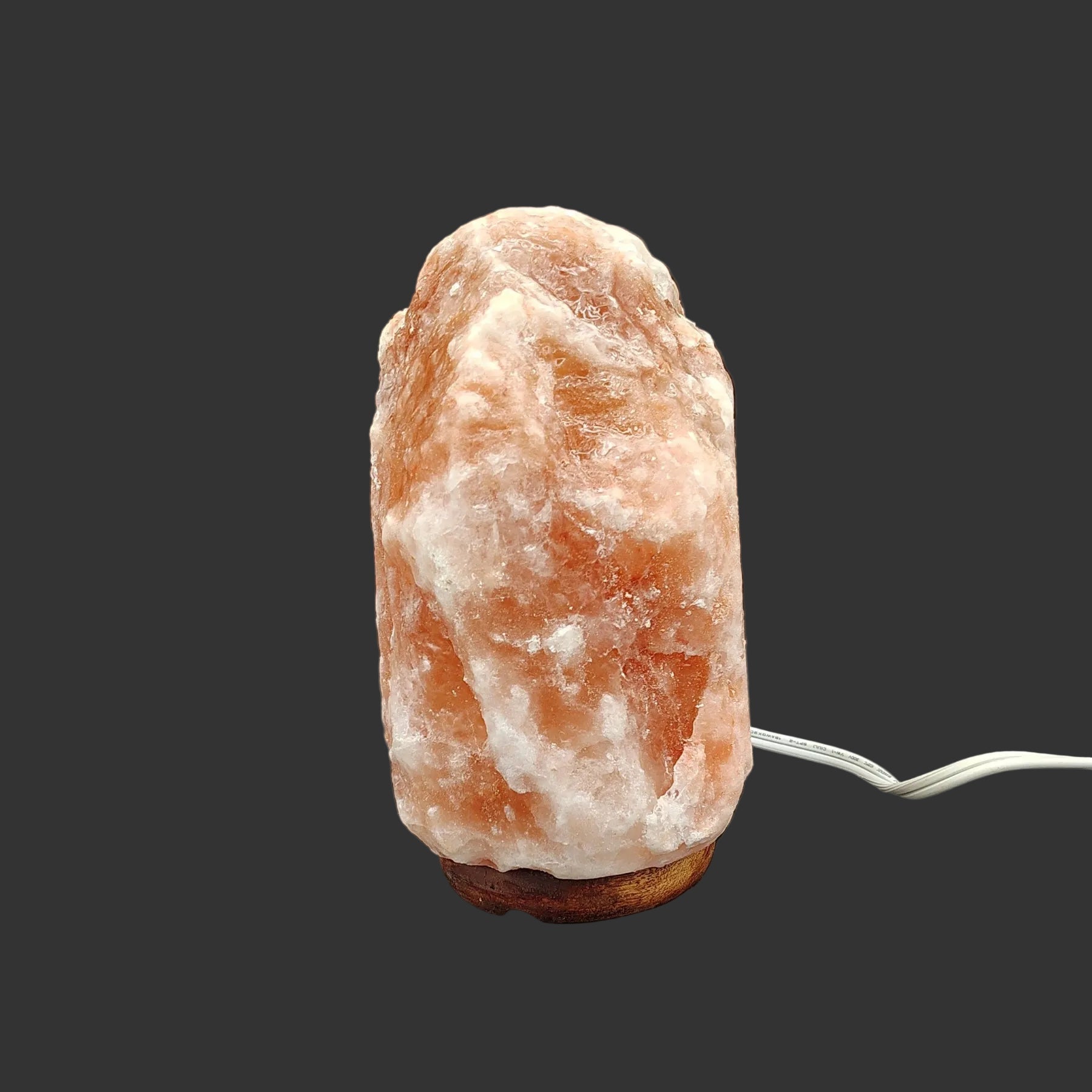 Right side of this pink Himalayan salt lamp in front of a black background.