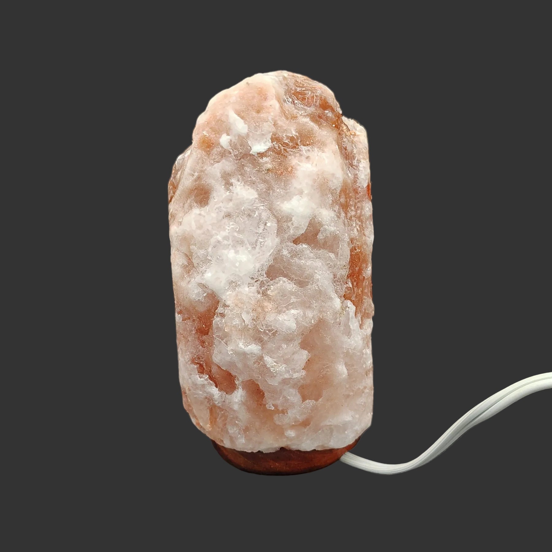 The left side of this pink Himalayan salt lamp in front of a black background.
