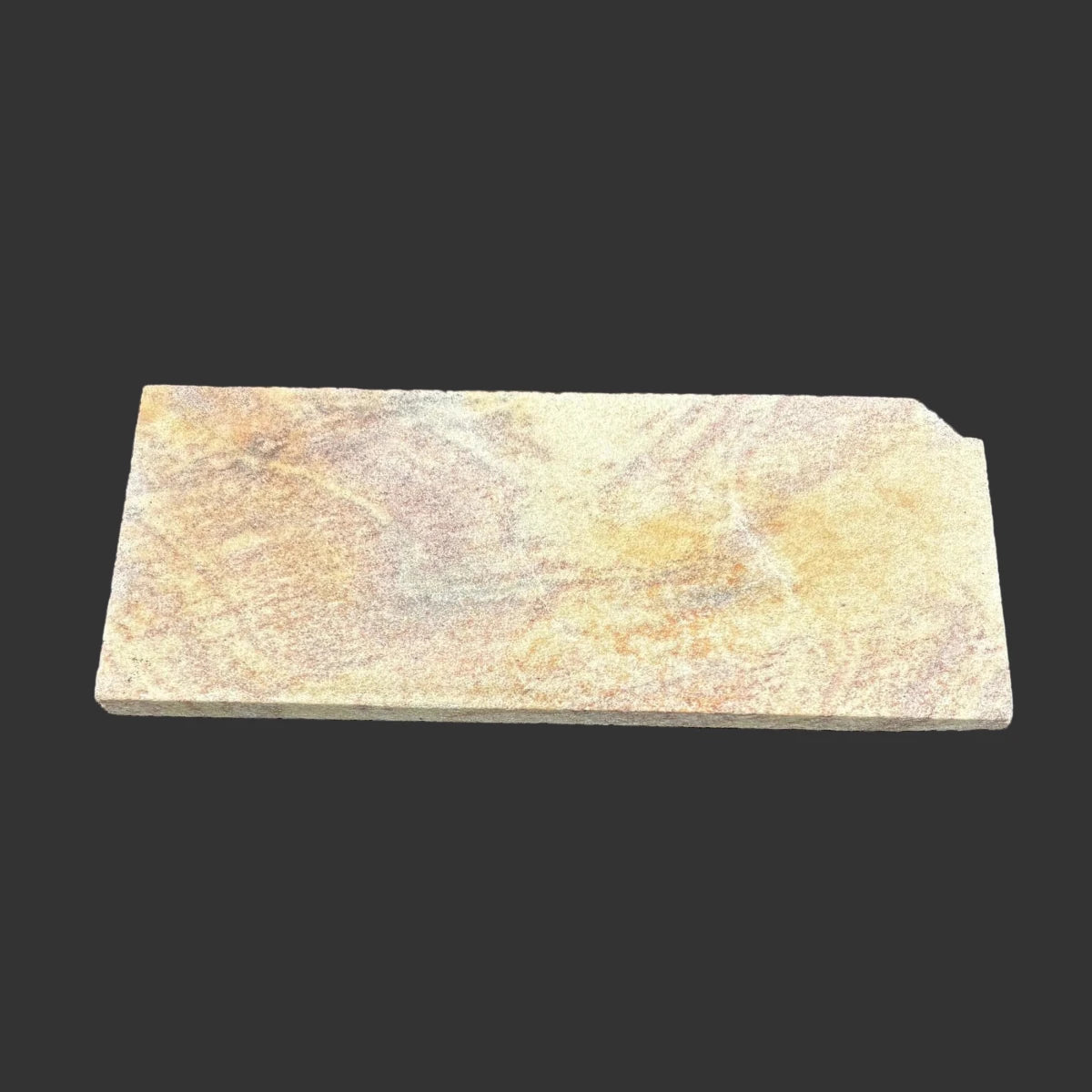 This is the back side of this novaculite sharpening stone in front of a black background.