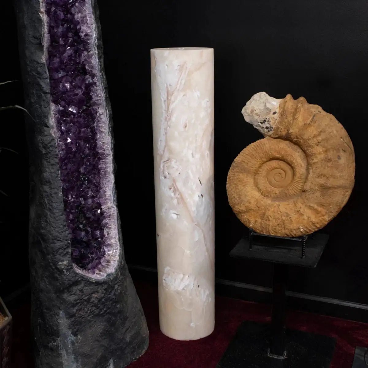 Amethyst crystal, marble column, and ammonite fossil on a dark background
