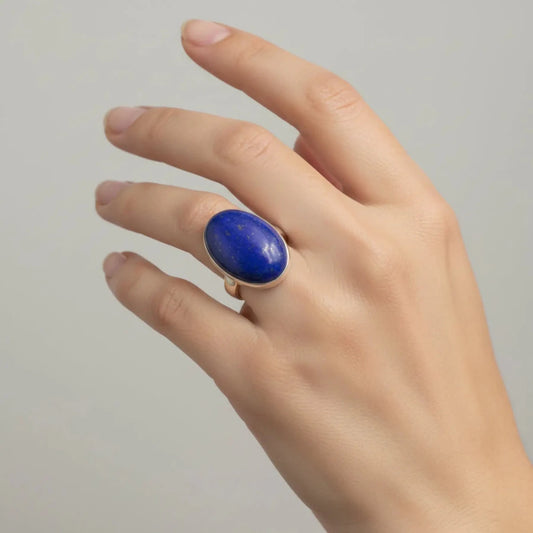 Oval blue Lapis and sterling silver ring on a woman's ring finger.