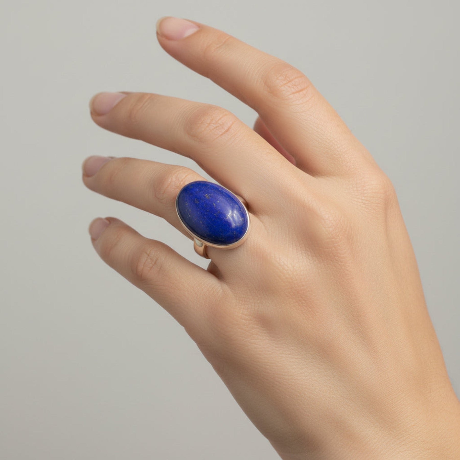 Oval blue Lapis and sterling silver ring on a woman's ring finger.