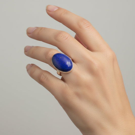 Oval blue Lapis and sterling silver ring on a woman's ring finger.