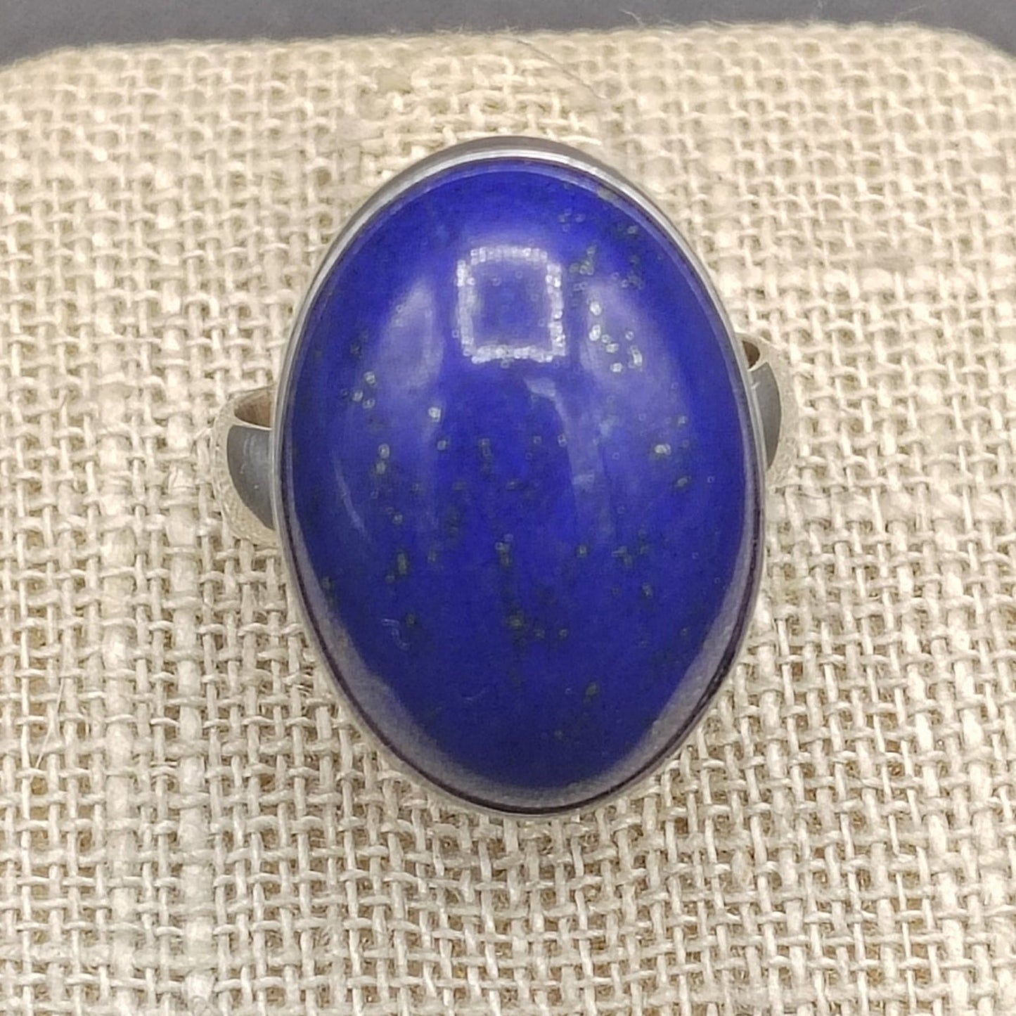 Close up of blue Lapis gemstone on a beige ring stand.