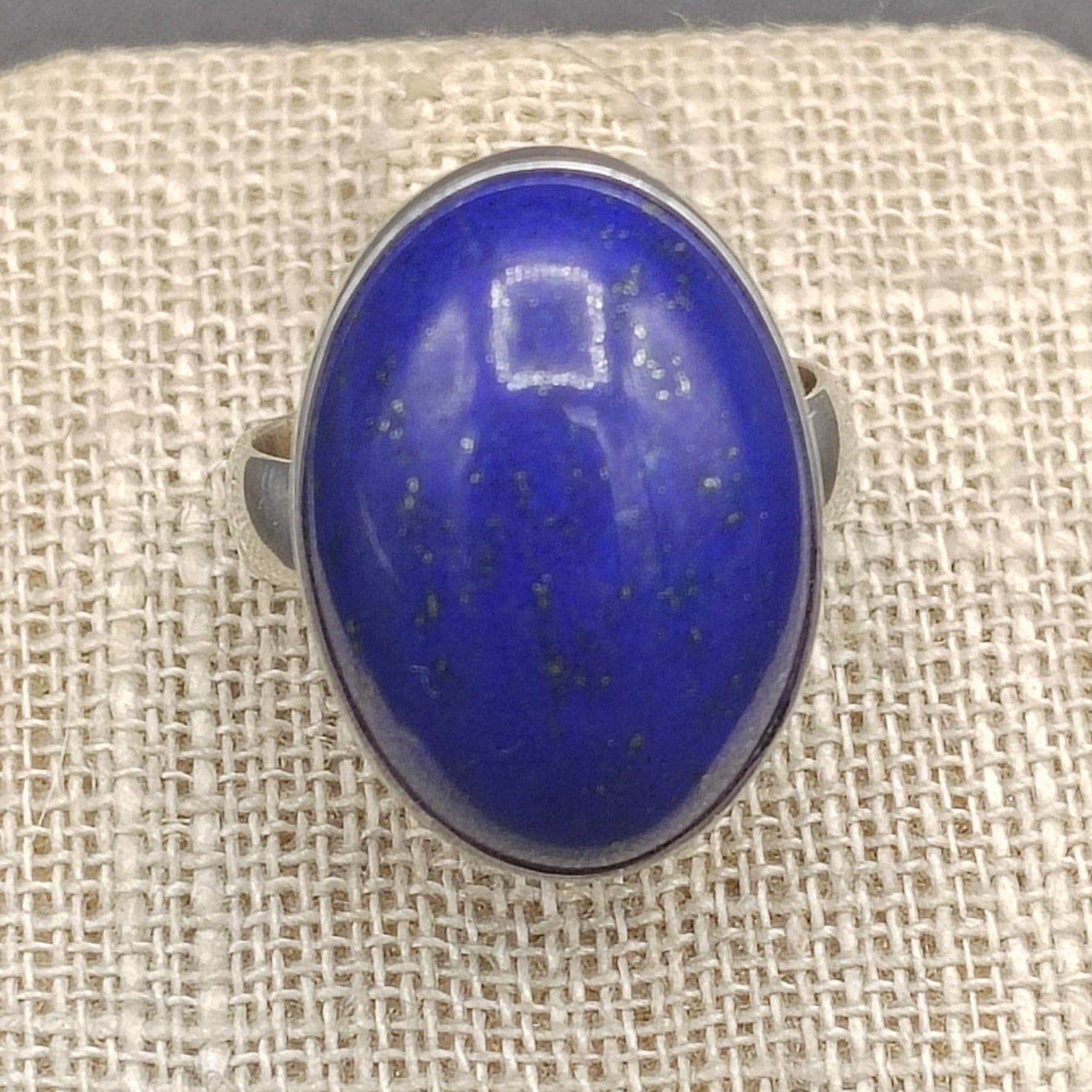 Close up of blue Lapis gemstone on a beige ring stand.