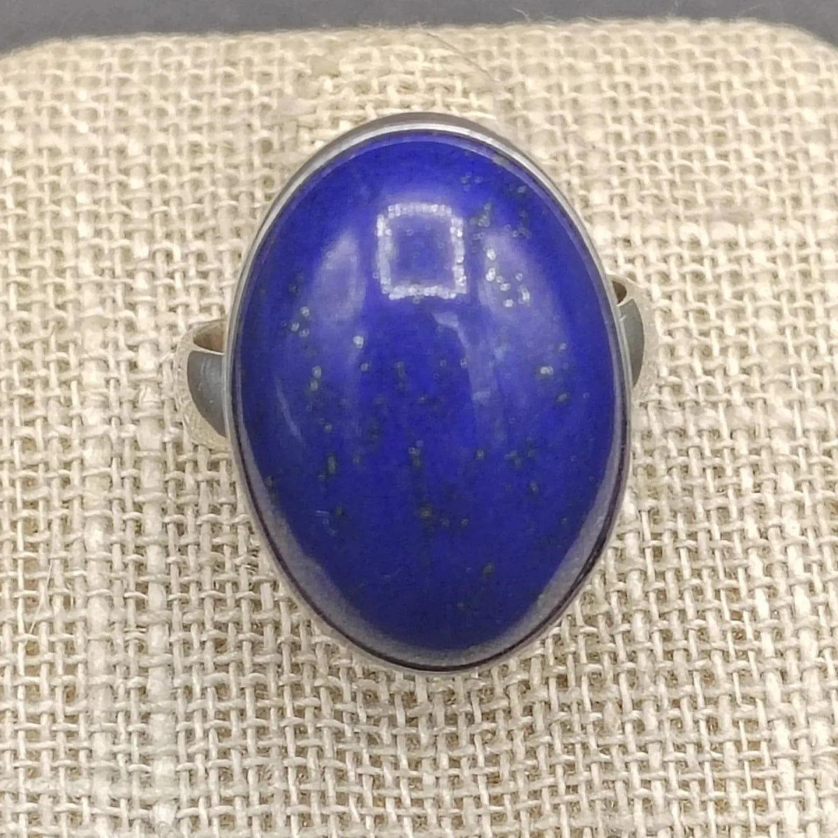Close up of blue Lapis gemstone on a beige ring stand.