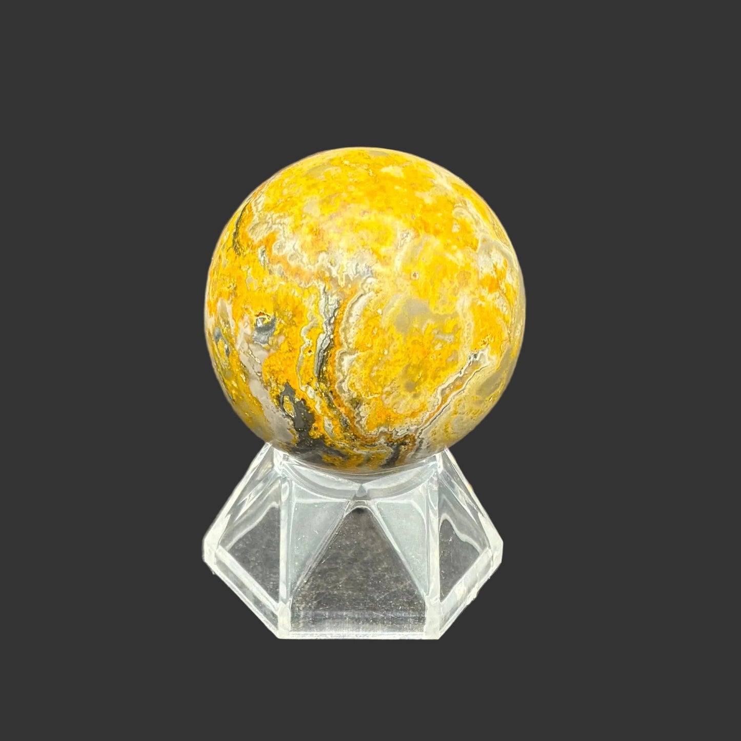This is the right side of this polished Bumblebee Jasper sphere, in front of a black background.