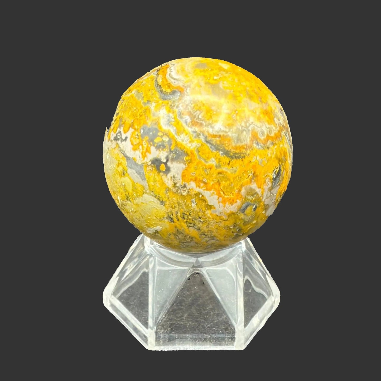 This is the back side of this polished Bumblebee Jasper sphere, in front of a black background.