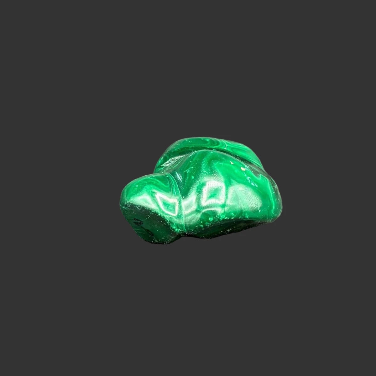 Side view of this polished malachite specimen, in front of a black background.