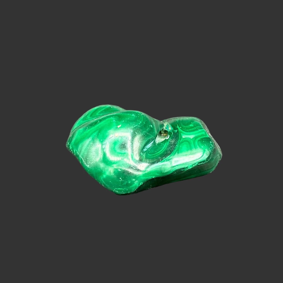 Back side of this polished malachite specimen, in front of a black background.
