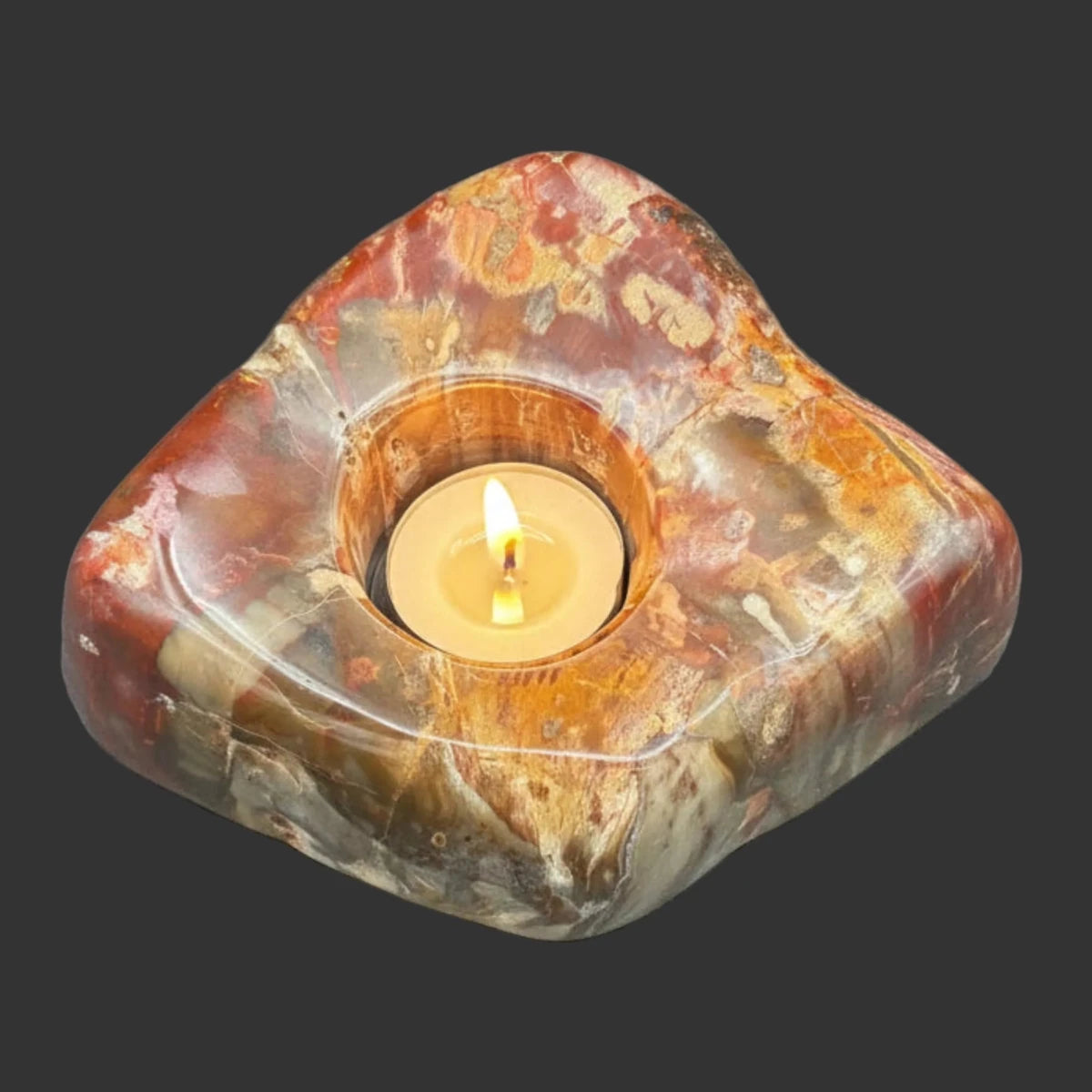 Top view of this polished petrified wood candle, with the candle lite, and in front of a black background.