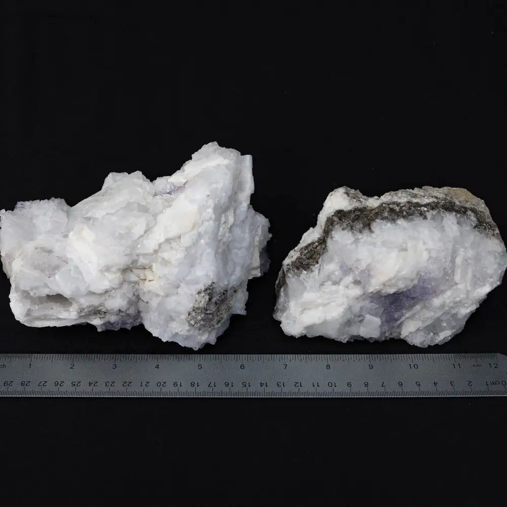 Tow white and purple rocks with a metal ruler in the front
