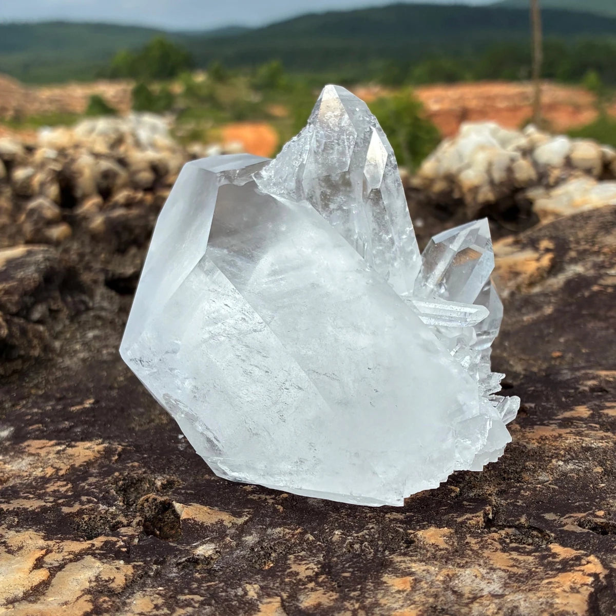 Right side of this Quartz crystal cluster in front of a outdoor setting.