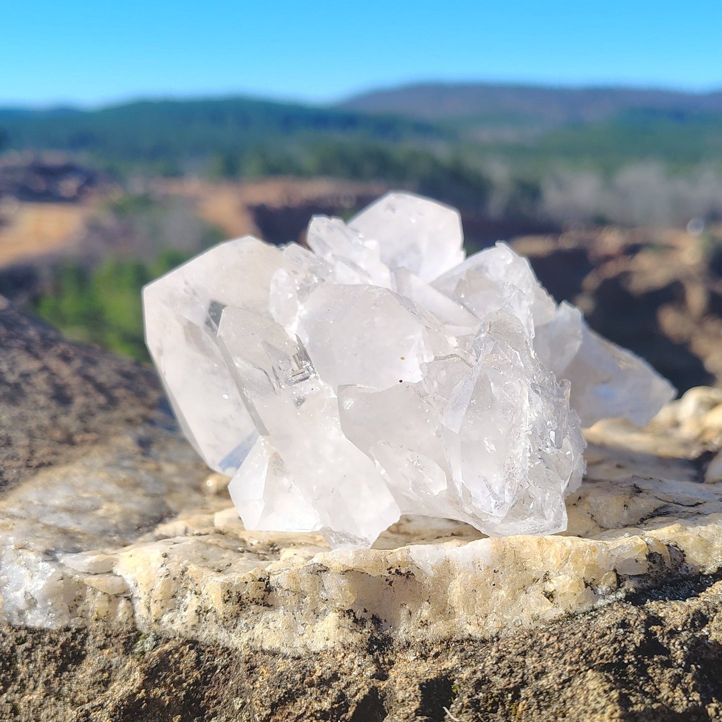 This is the left side of this Quartz crystal cluster in front of a natural outdoor background.