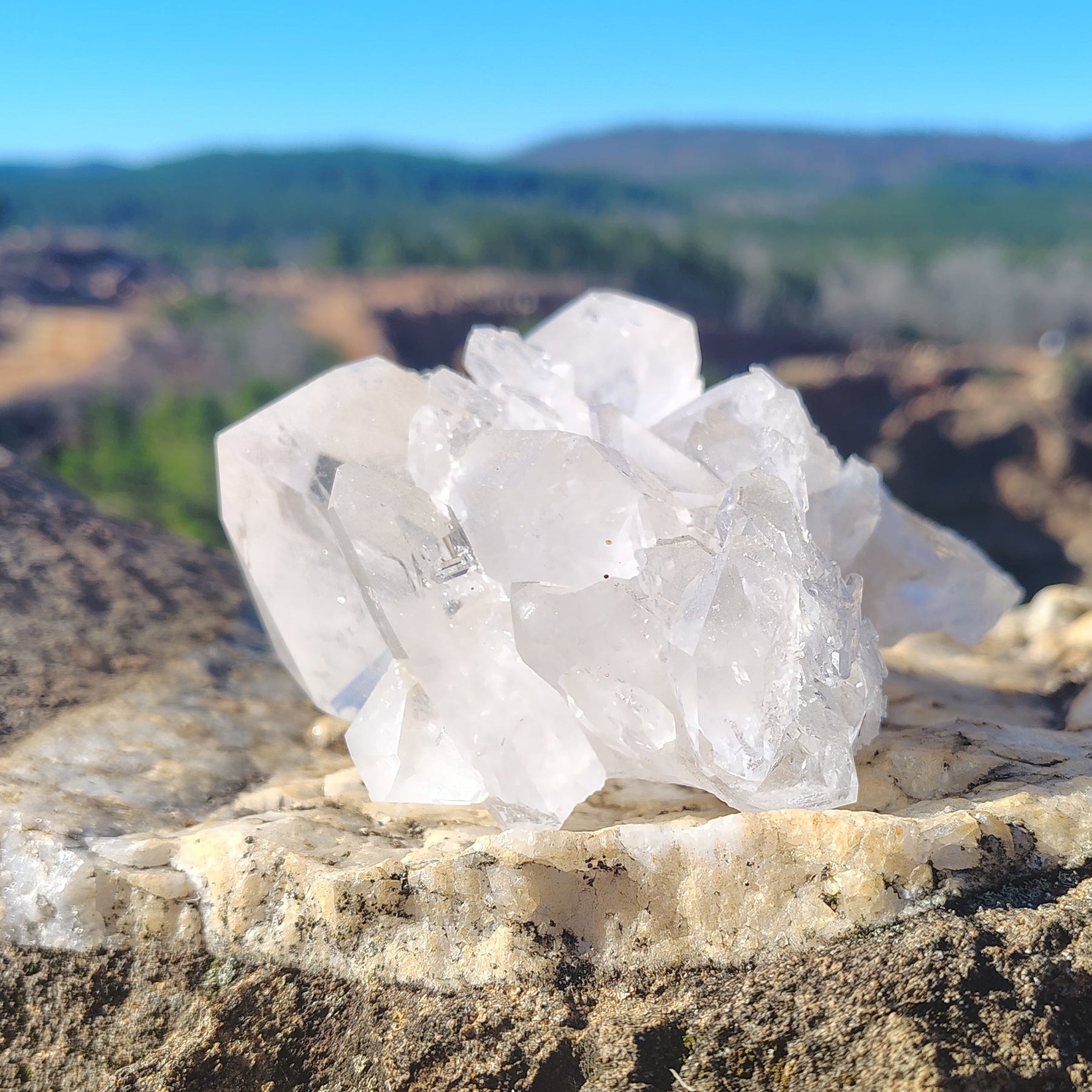 This is the left side of this Quartz crystal cluster in front of a natural outdoor background.
