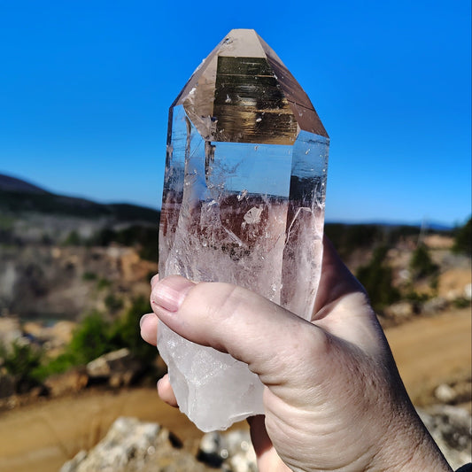 Front side of pristine clear quartz crystal point held in front of the Ron Coleman crystal mine.