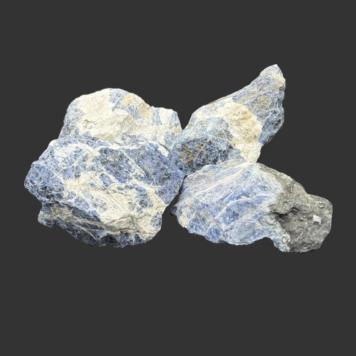 Group picture of this set of 4 pieces of sodalite, in front of a black background.
