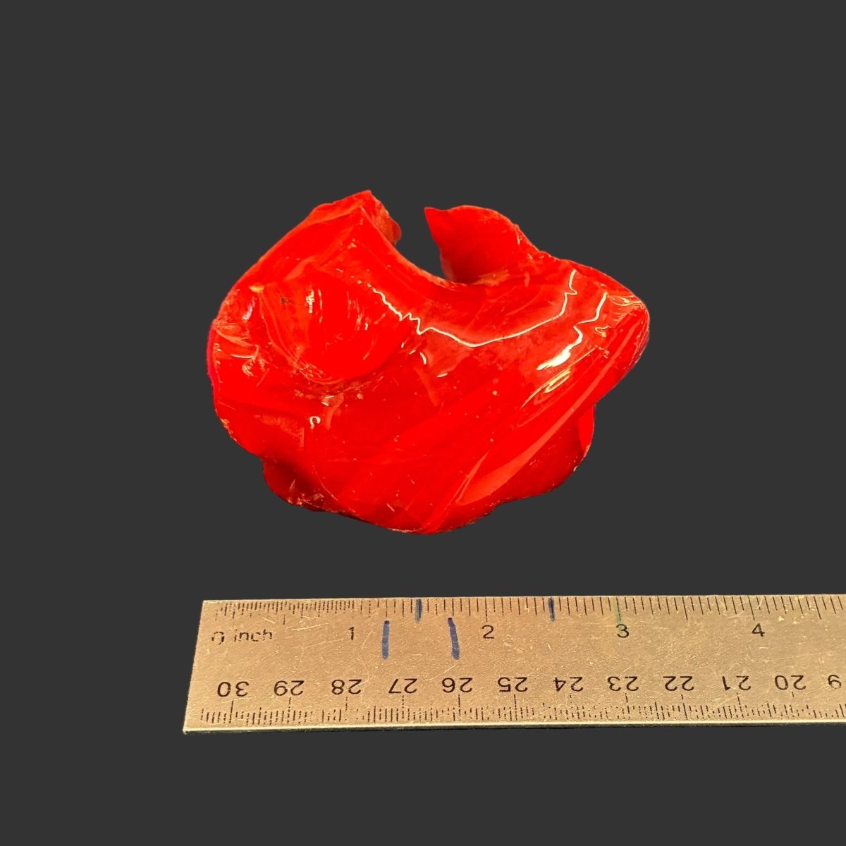Smallest piece of red slag glass that is included in this listing, in front of a black background.