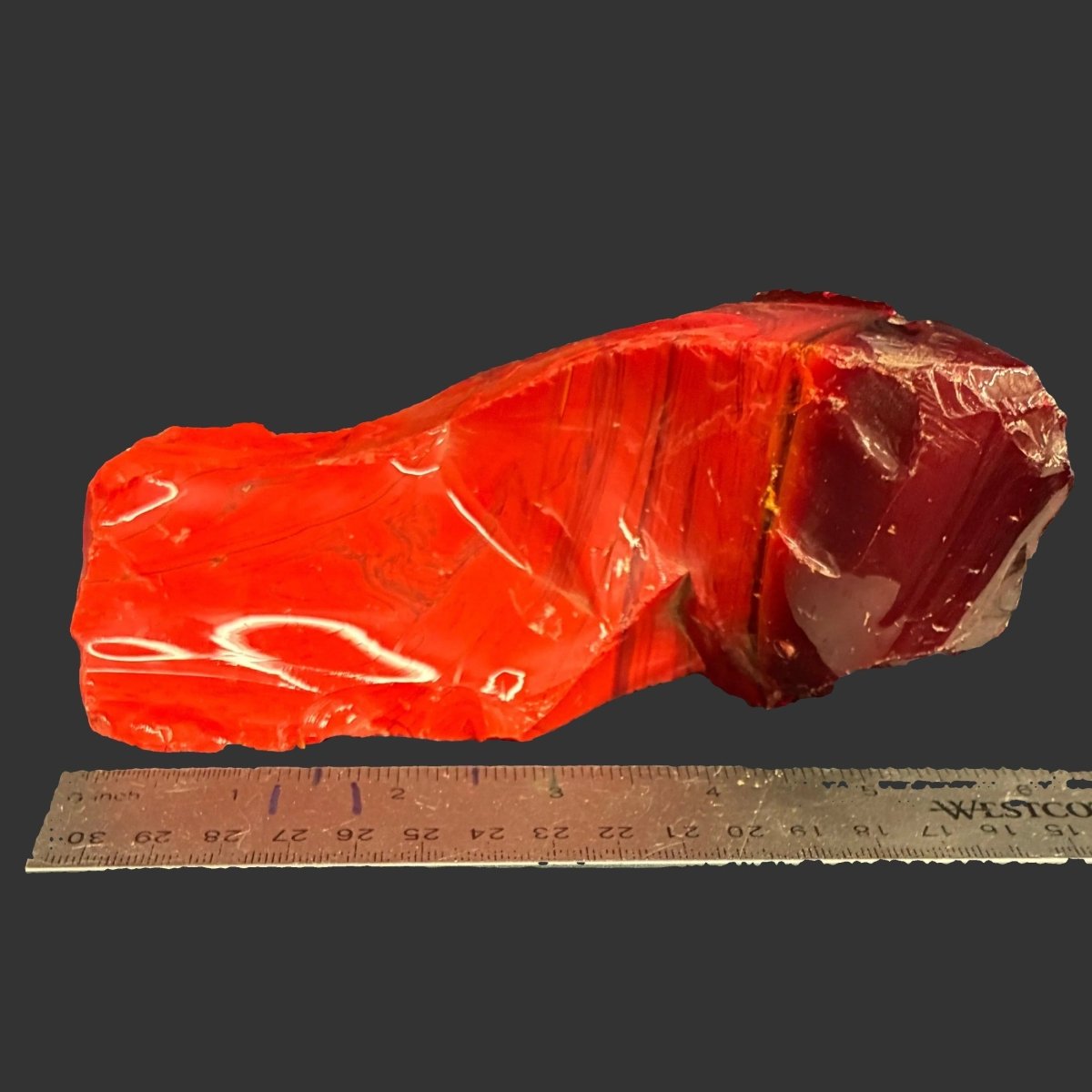 This is the biggest piece of red slag glass included with this listing, in front of a black background.