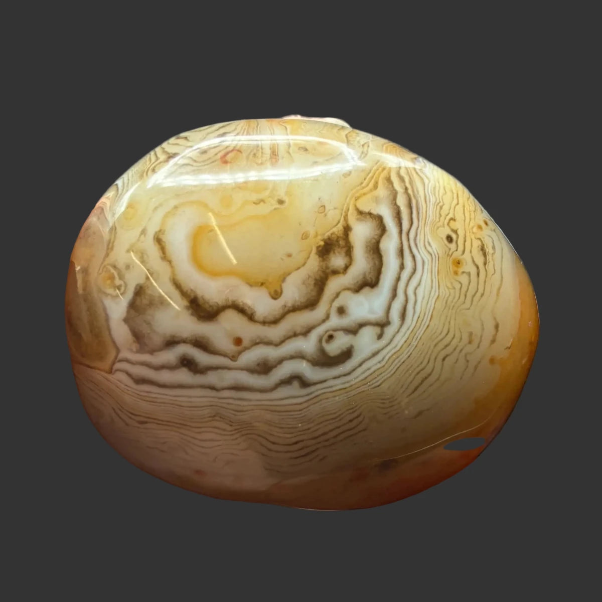 Front side of this polished Sardonyx palm stone, in front of a black background.