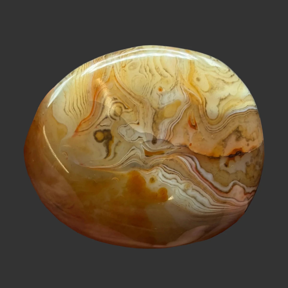 This is the back side of this polished Sardonyx palm stone, in front of a black background.