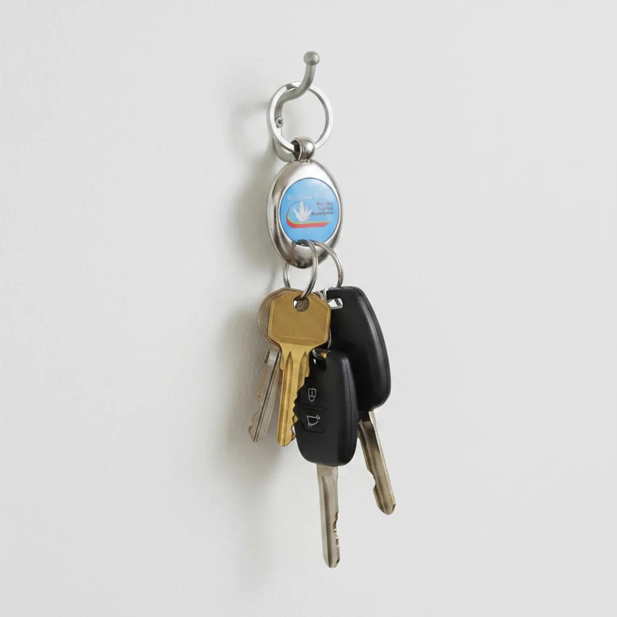 RCM keychain with keys added to it, hanging on a wall hook.