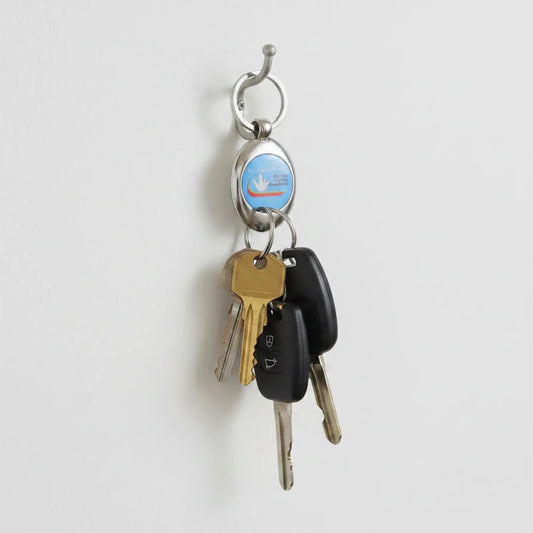 RCM keychain with keys added to it, hanging on a wall hook.