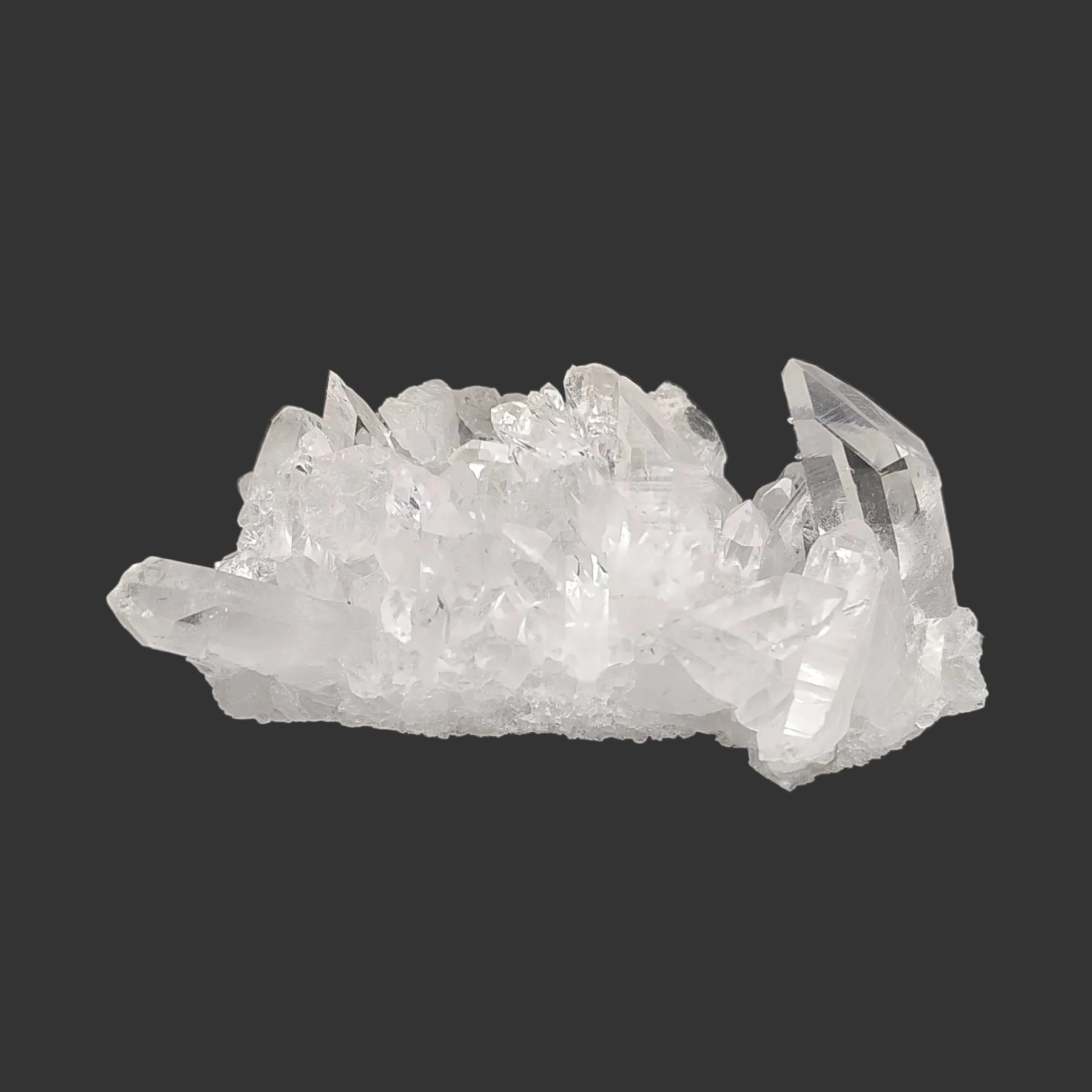 This is the front side of this clear and small Quartz crystal cluster in artificial light.