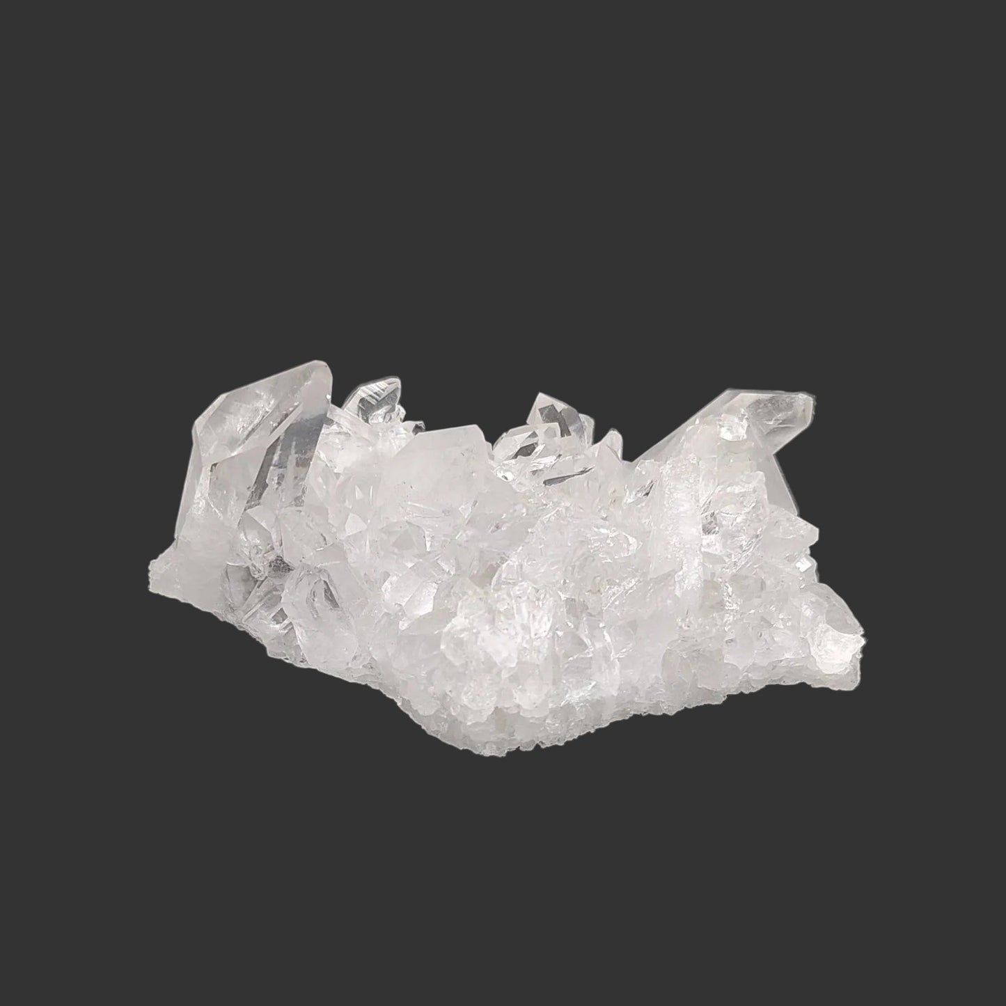 This is the back side of this clear small Quartz crystal cluster in artificial light.