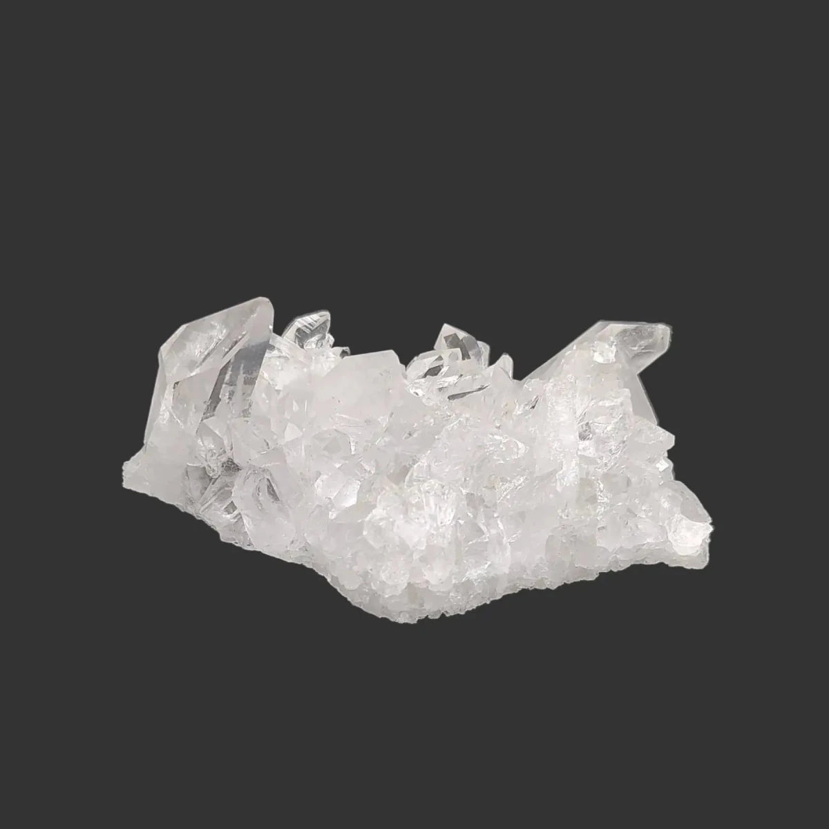 This is the back side of this clear small Quartz crystal cluster in artificial light.