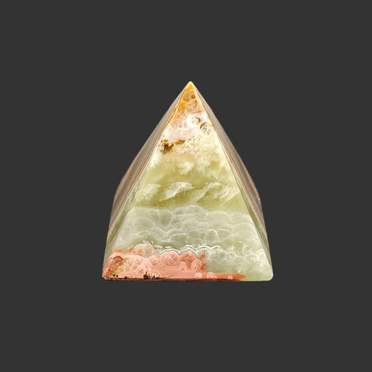 The front view of this green onyx pyramid is mostly green, with a touch of orange and brown.