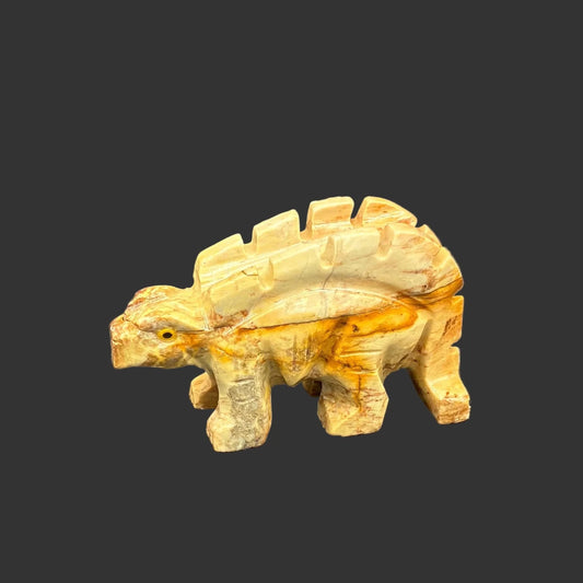 Left side of this polished soapstone Stegosaurus, in front of a black background.