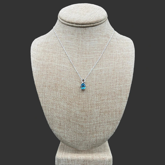 Front view of this sterling silver and blue topaz necklace, in front of a black bacground.