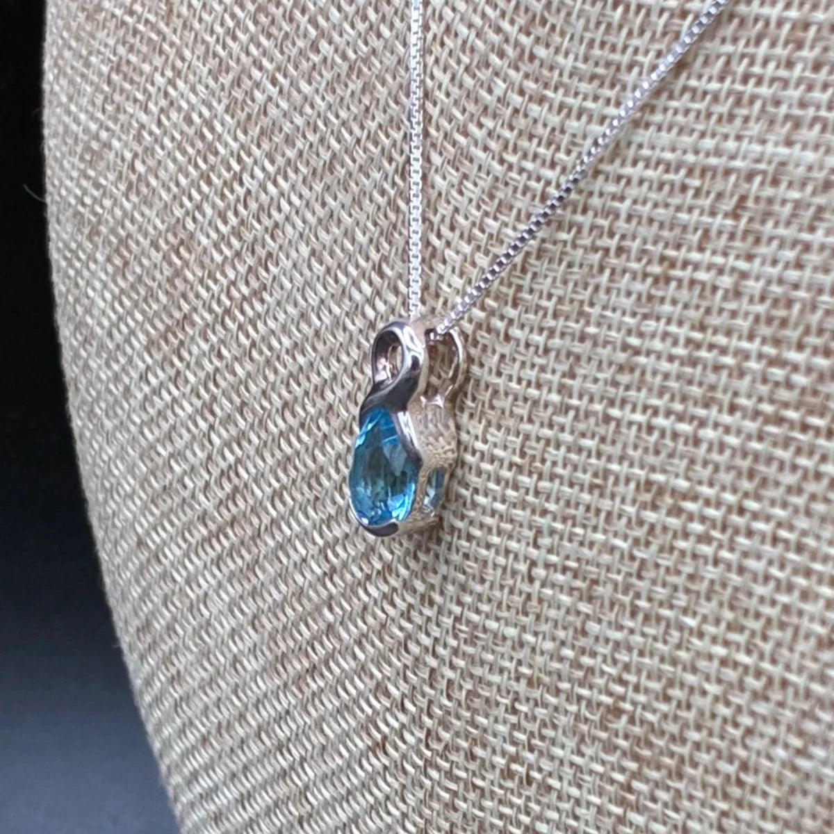 Side view of this sterling silver and blue topaz necklace.