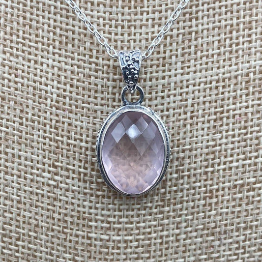 Close Up Of Rose Quartz Pendant, It Is Light Pink In Color And Oval In Shape