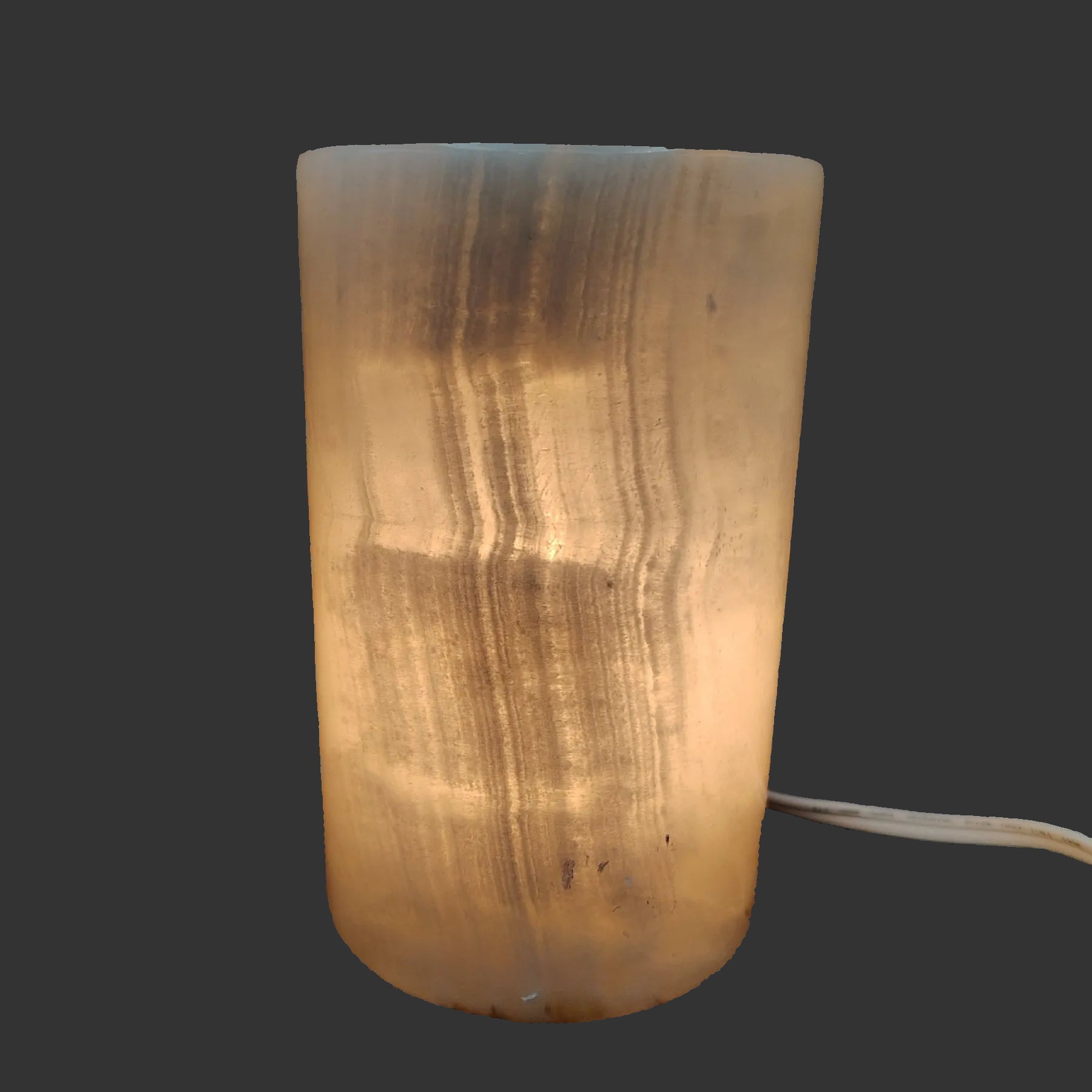 Polished cream-colored Onyx cylinder lamp, with the lamp turned on.