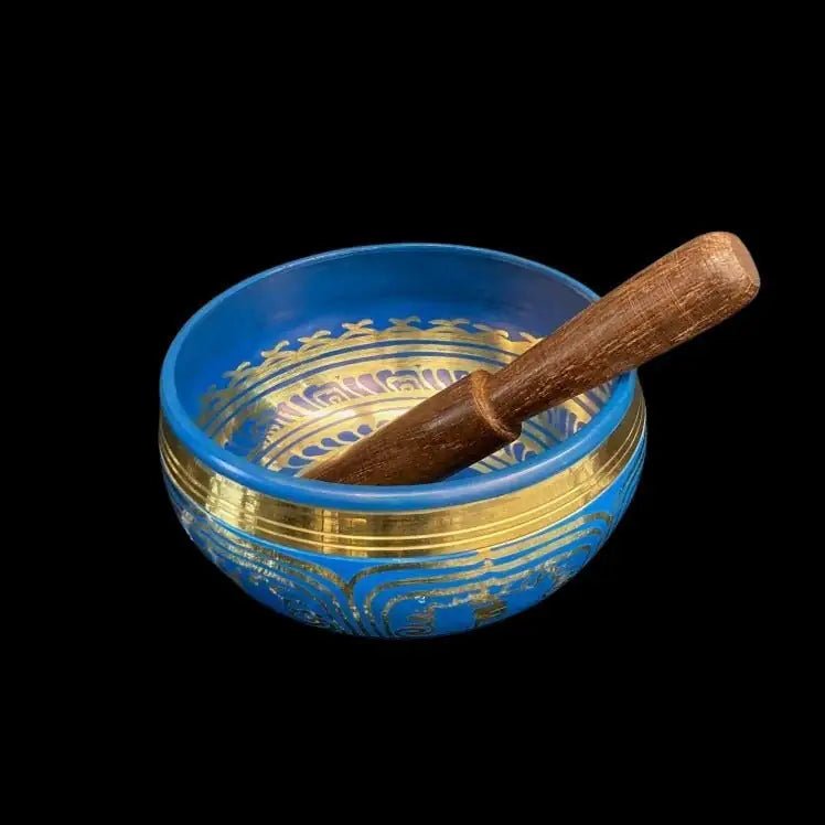Blue Singing Bowl with brass showing at the top and brass chakra symbols on the sides.  There is a wooden striking tool sitting inside the bowl