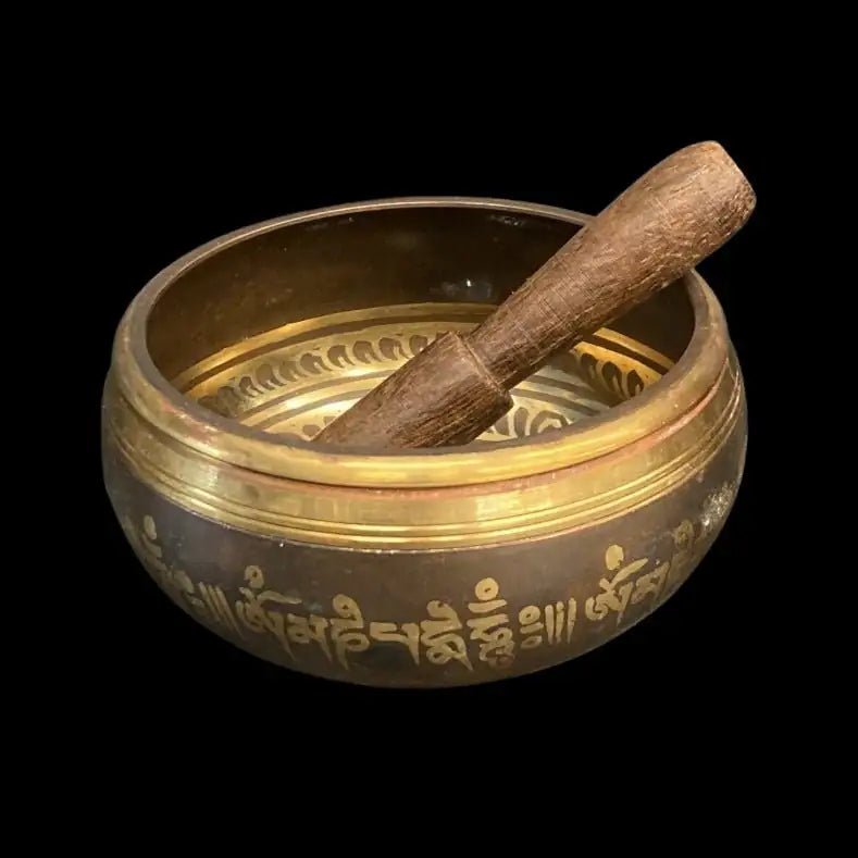 Brass Singing Bowl with brown paint that has been heated on the outside and inside of the bowl.  There a Chakra symbols throughout and a wooden striking mallet laying inside the bowl