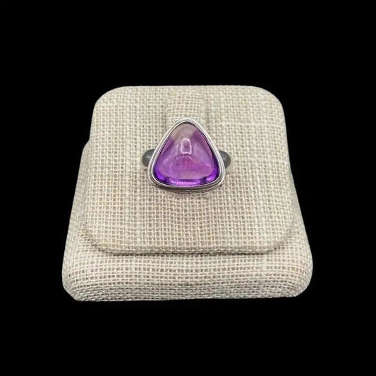 Sterling Silver And triangular shaped, rounded cabochon cut Amethyst Gemstone. The ring is in a beige ring display