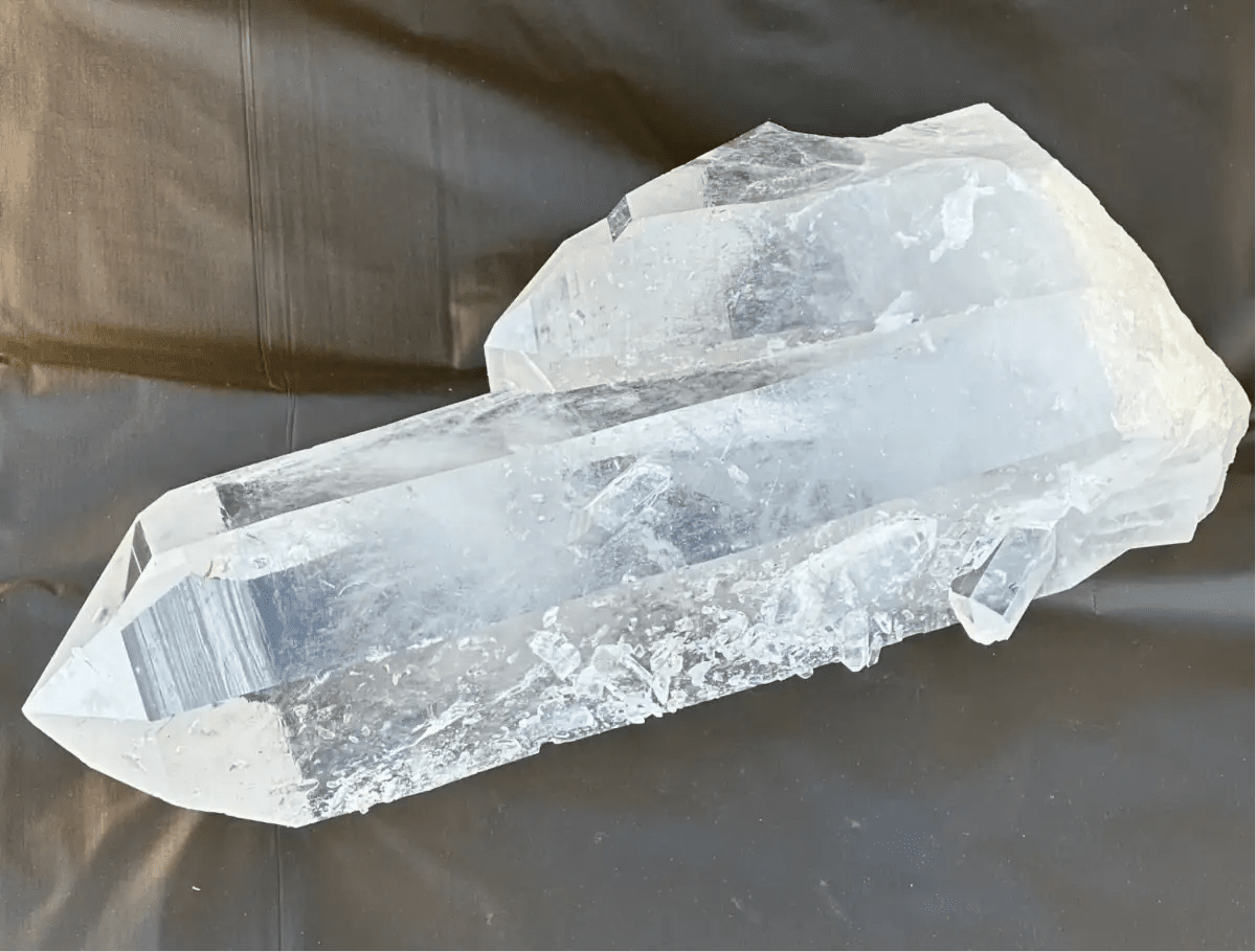 Outdoor close up image of a clear quartz crystal point with a tabular crystal growth