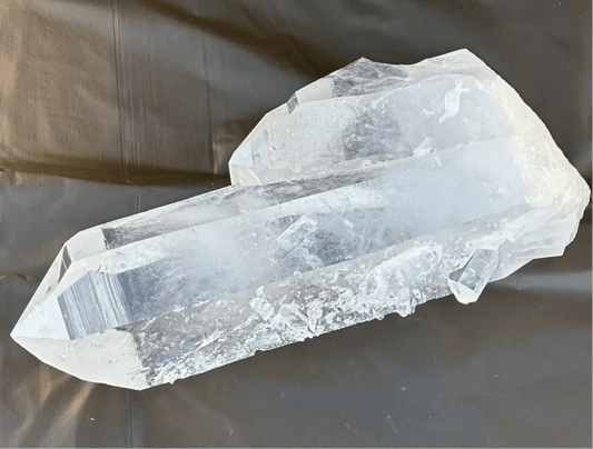 Outdoor close up image of a clear quartz crystal point with a tabular crystal growth