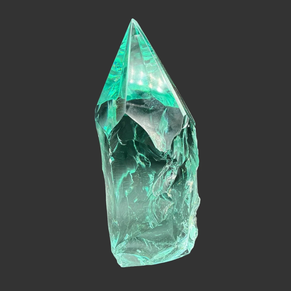 Left side of this blue green slag glass freeform, in front of a black background.