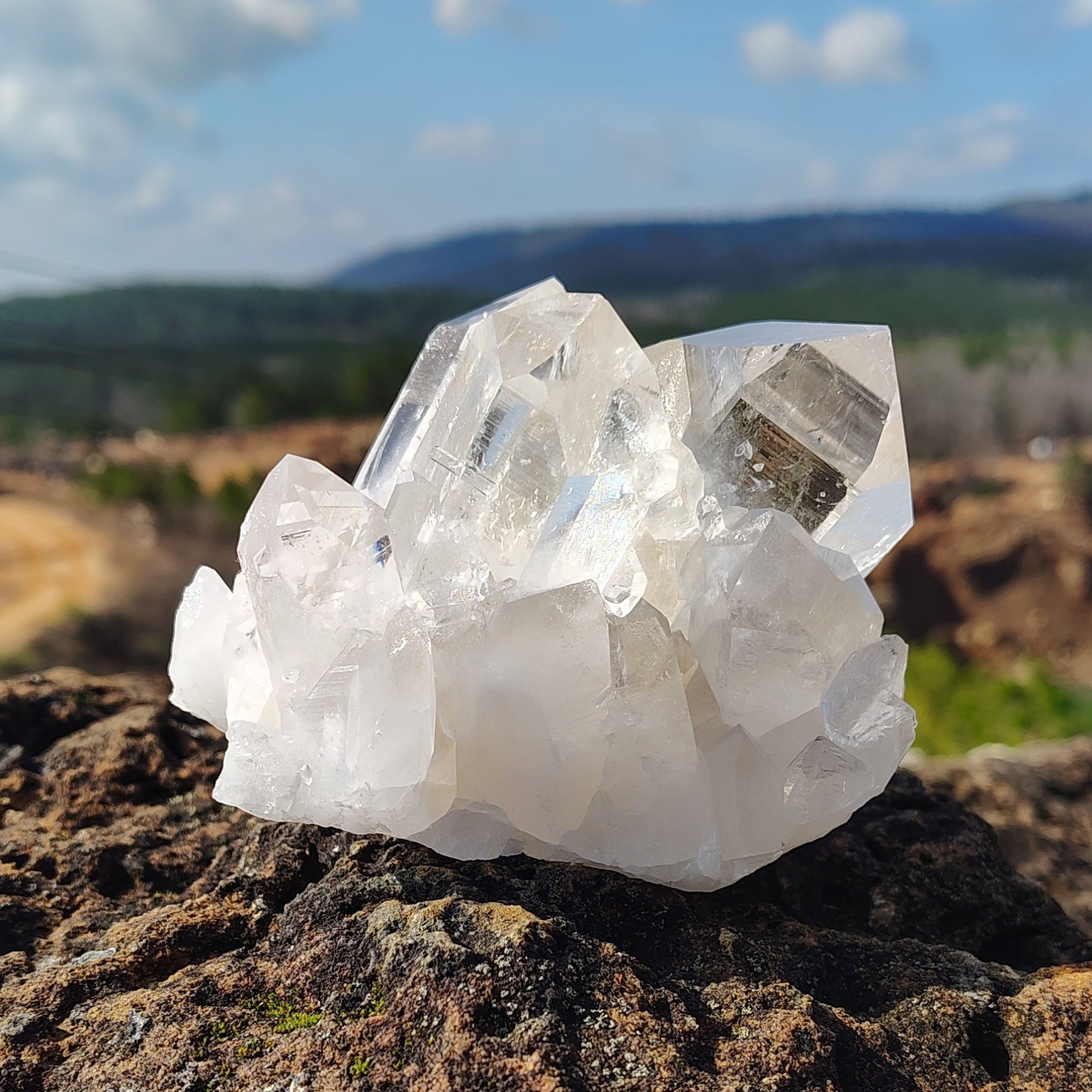 This is the front side of this water clear quartz cluster in outdoor natural light, overlooking the crystal mine.