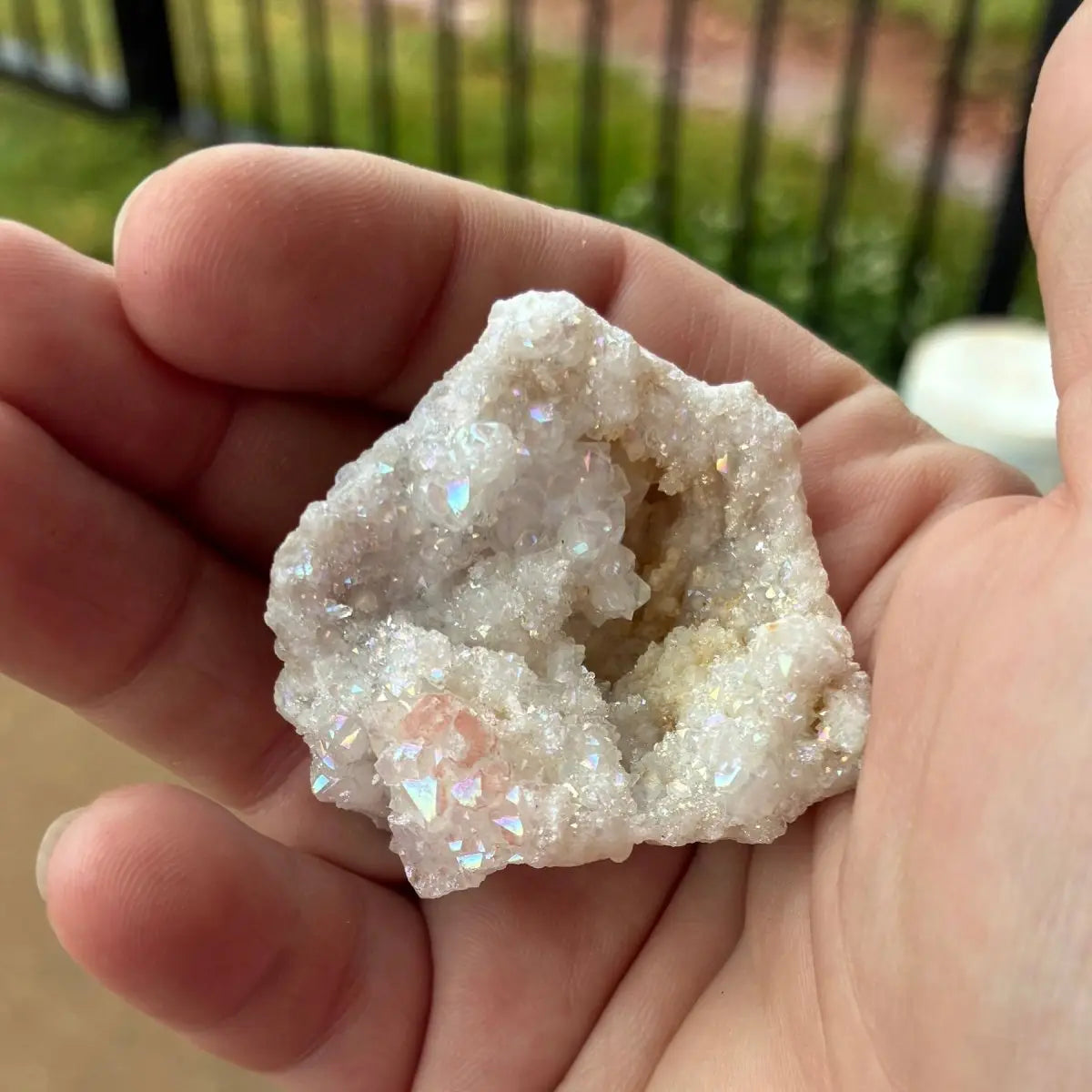 Hand holding a crystal rock with a blurred outdoor background