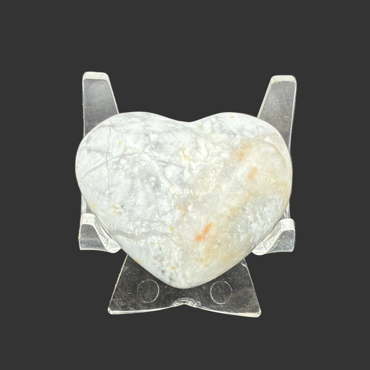Polished white Howlite heart, in front of a black background.