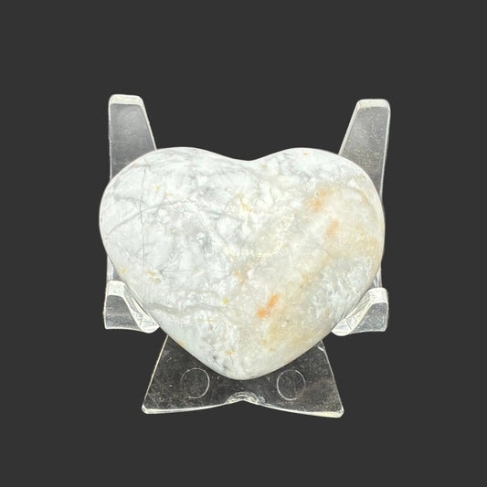 Polished white Howlite heart, in front of a black background.