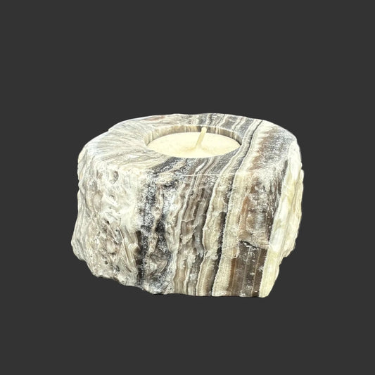 Front side of this zebra calcite candle holder, in front of a black background.